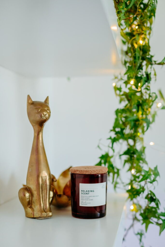 Relaxáló illatgyertya, arany macskaszobor és fényfüzér kreatív otthoni irodában
