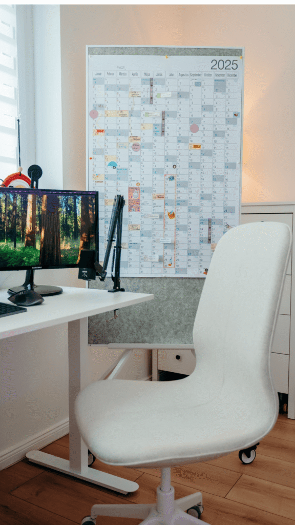 Fehér gurulós tábla éves falinaptárral, női vállalkozó kreatív otthoni irodájában